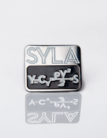 Значок Syla. Колір чорний. Матеріал: метал  Ширина - 28 мм
Висота - 24 мм.